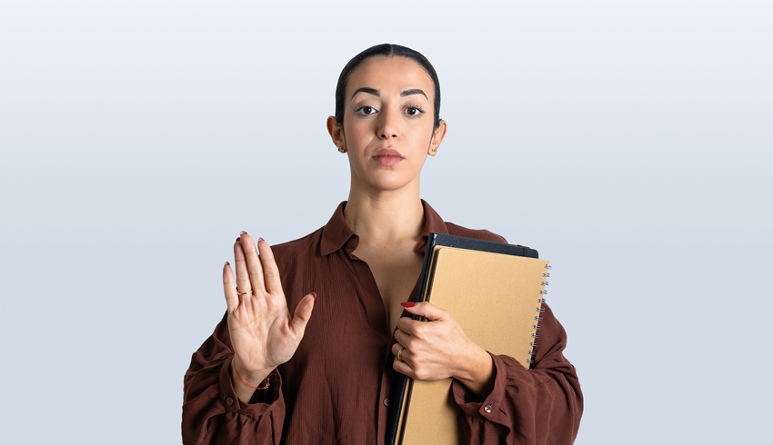 Professionally dressed woman holding papers with one arm while raising the other, representing behaviour management strategies
