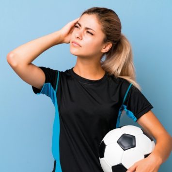 Photo of teenage girl dressed for football practice looking thoughtful, representing PE teaching