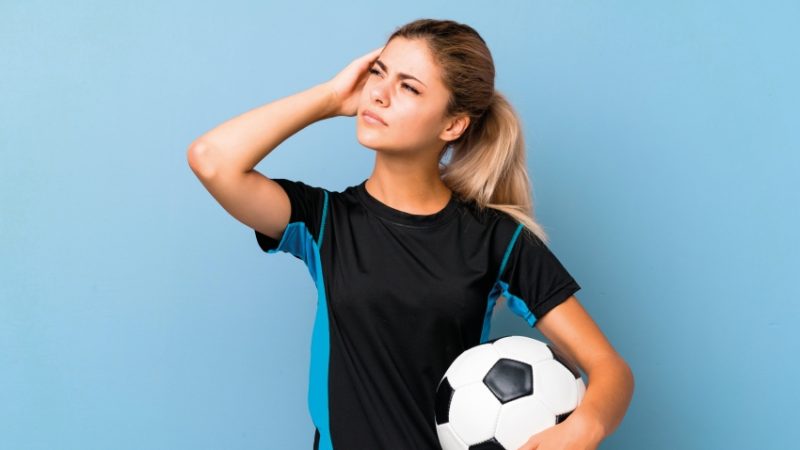 Photo of teenage girl dressed for football practice looking thoughtful, representing PE teaching