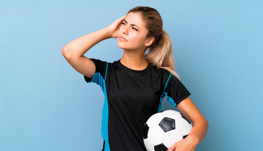 Photo of teenage girl dressed for football practice looking thoughtful, representing PE teaching