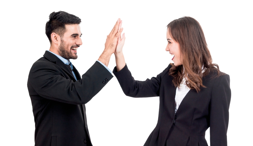 Photo of professionally attired man and woman giving each other a high five
