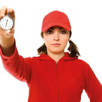 Young female sports teacher holding up a stopwatch, representing coaching models