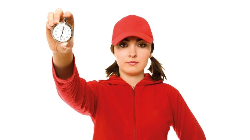 Young female sports teacher holding up a stopwatch, representing coaching models