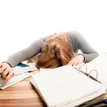 Photo of a teenaged girl seemingly restng on a selection of revision materials