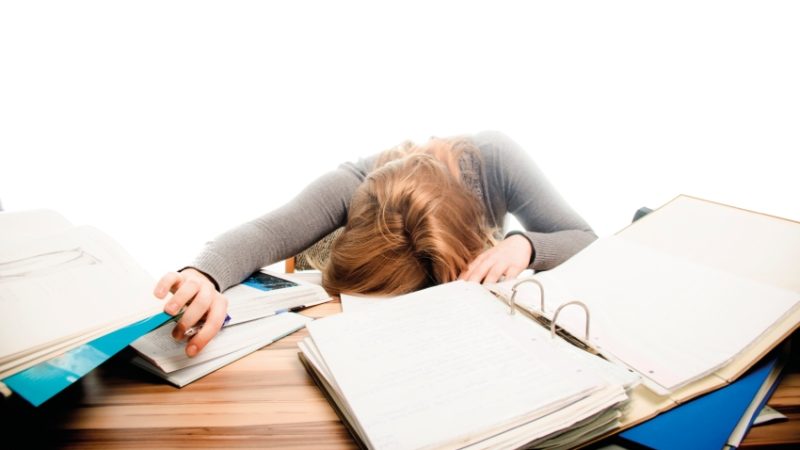 Photo of a teenaged girl seemingly restng on a selection of revision materials