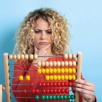 Photo of confused woman holding an abacus, representing maths teachers