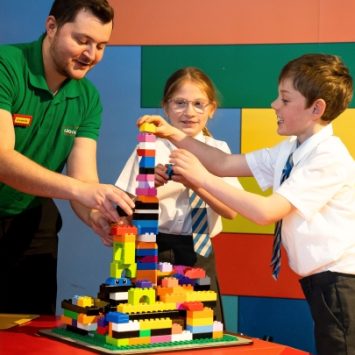 Two Key Stage 2 pupils building with LEGO, supported by an adult workshop leader
