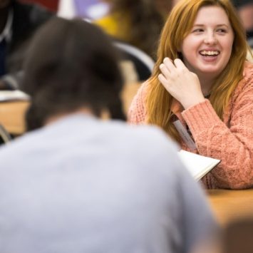 A primary school teacher sitting at a table smiling