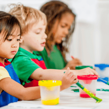 Three young children painting, representing art assessment