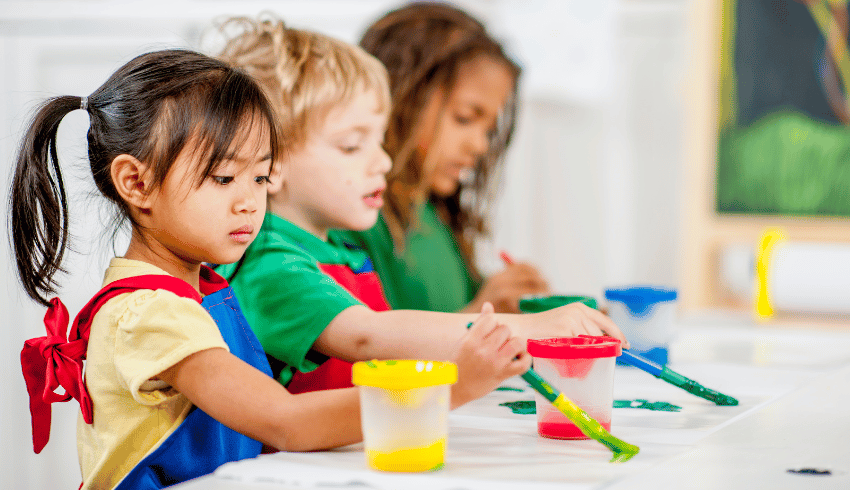 Three young children painting, representing art assessment