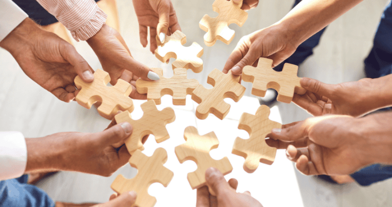 Hands holding jigsaw pieces together, representing collaboration at Badock's Wood Primary