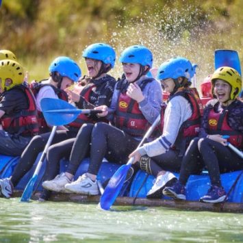 A group of school children paddling a raft