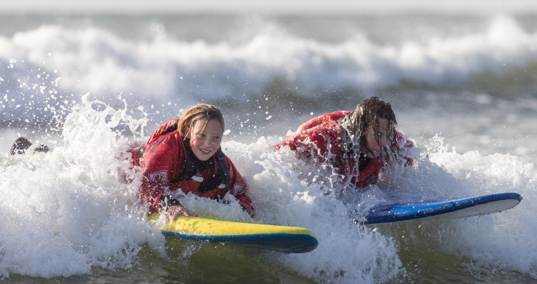 Two school girls bodyboarding in the sea