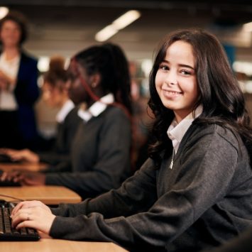A secondary school girl sitting at a computer in a classroom
