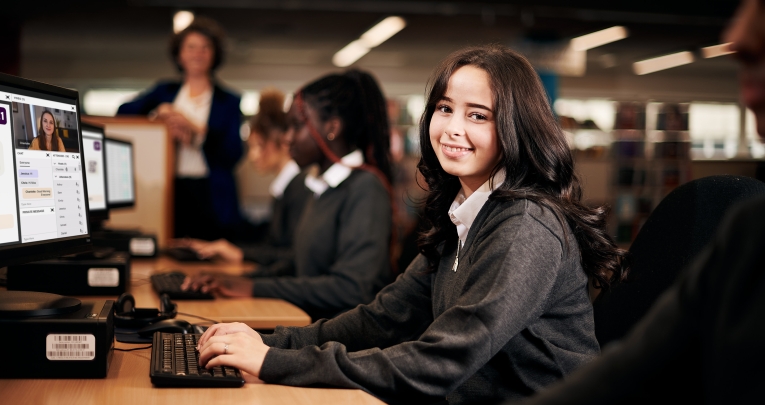 A secondary school girl sitting at a computer in a classroom