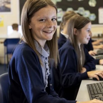 A primary schoolgirl sitting at a desk with a computer