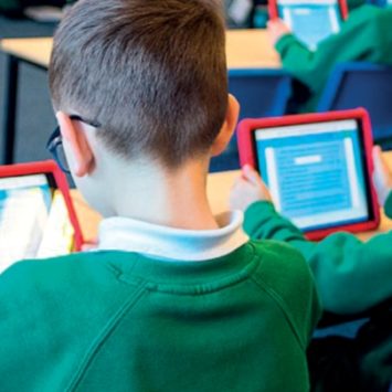 Primary school students sitting and working on tablets