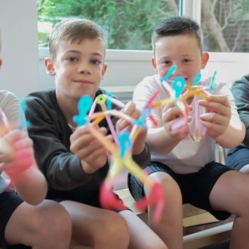 Four schoolboys holding Strawbees resources