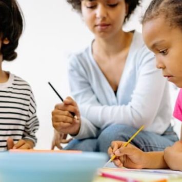 Two children sitting at a table and painting