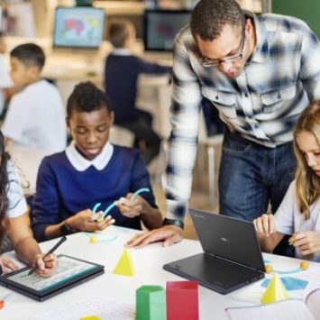 A group of primary school children at a desk using ASUS laptops
