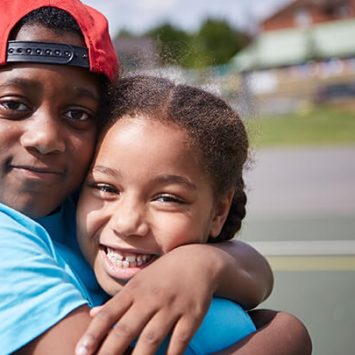 Two smiling primary school pupils hugging each other