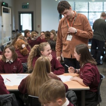 A group of secondary school students in a classroom with a teacher