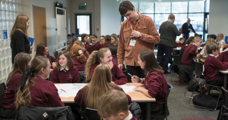 A group of secondary school students in a classroom with a teacher