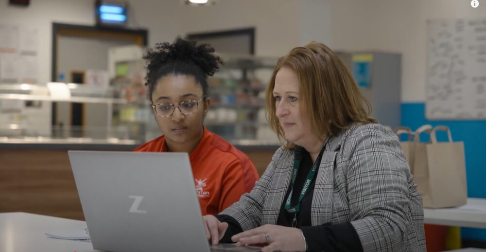 A teacher and student sitting together looking at a laptop
