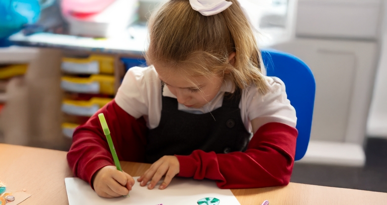 A primary school girl writing at a desk.