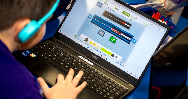 A school child working with a laptop in a classroom