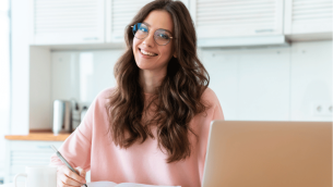 Female teacher sitting at desk with notepad and laptop, representing Practitioner Enquiry