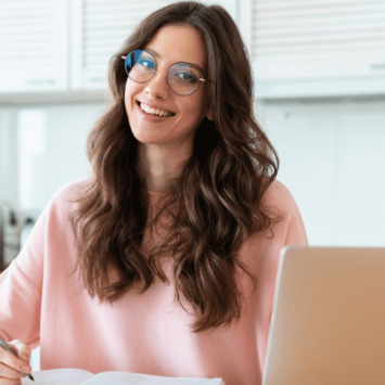 Female teacher sitting at desk with notepad and laptop, representing Practitioner Enquiry