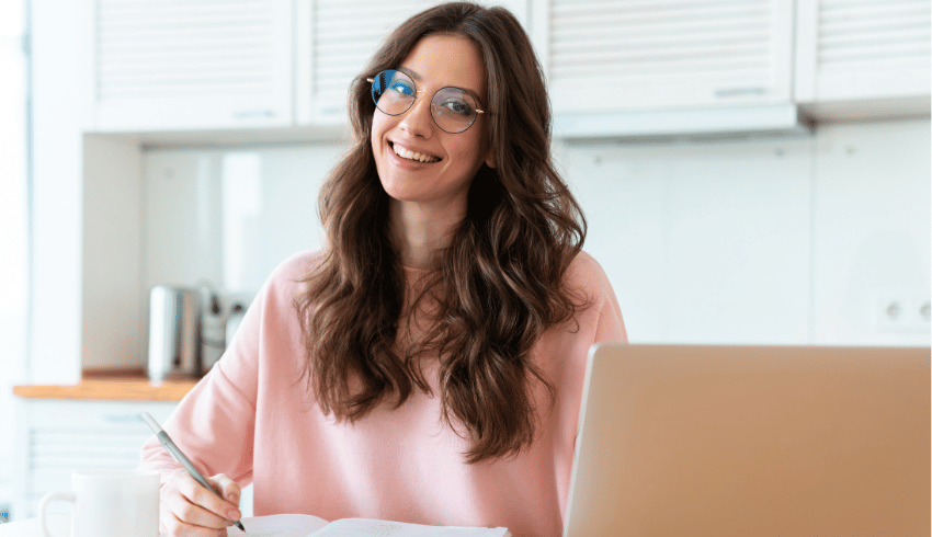 Female teacher sitting at desk with notepad and laptop, representing Practitioner Enquiry