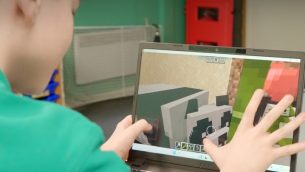 A school boy using a touchscreen on a laptop