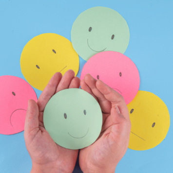 Hands holding smiley paper face, representing appreciative inquiry