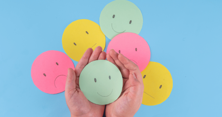 Hands holding smiley paper face, representing appreciative inquiry