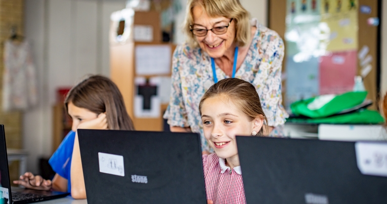 A teacher with two school girls working on laptops