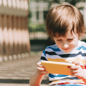 Young boy using phone, representing schools banning phones
