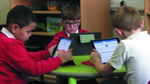 Three primary schoolboys using Clicker at a table