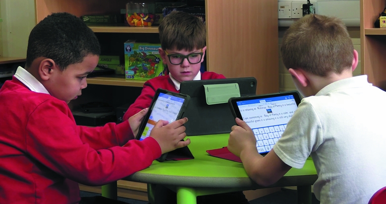 Three primary schoolboys using Clicker at a table