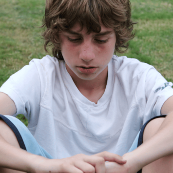 White working class boy sitting on field