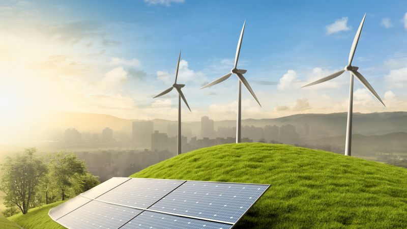 A solar panel on a hill; wind turbines below