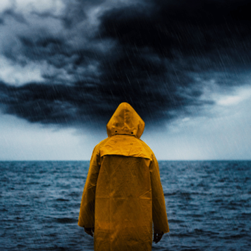 Person in yellow raincoat looking at storm, representing crisis communications