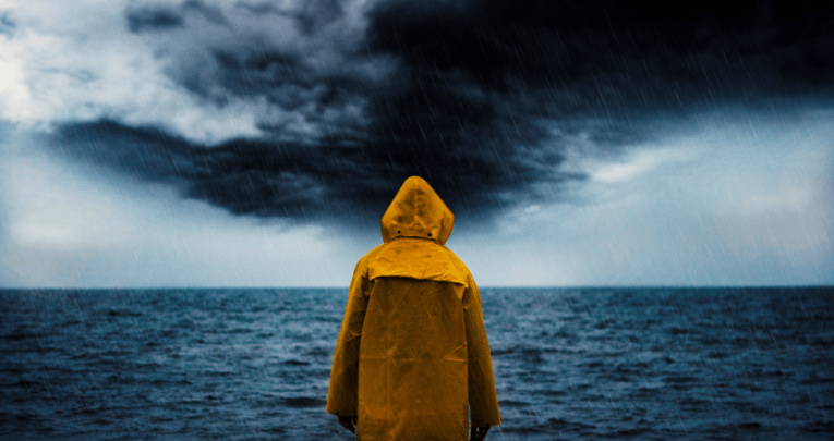 Person in yellow raincoat looking at storm, representing crisis communications