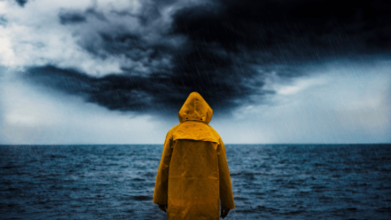 Person in yellow raincoat looking at storm, representing crisis communications