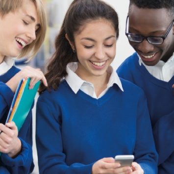 A group of secondary school students looking at a mobile phone