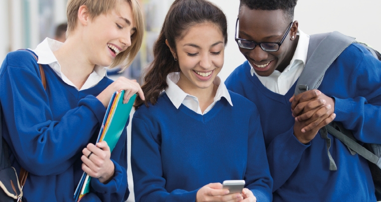A group of secondary school students looking at a mobile phone