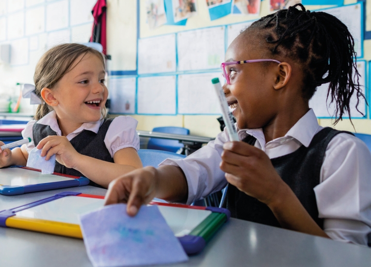 Two primary-aged school girls sitting at a desk