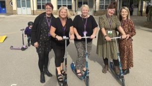 A group of teachers on scooters in a school playground