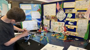 A young boy building LEGO in front of a poster display